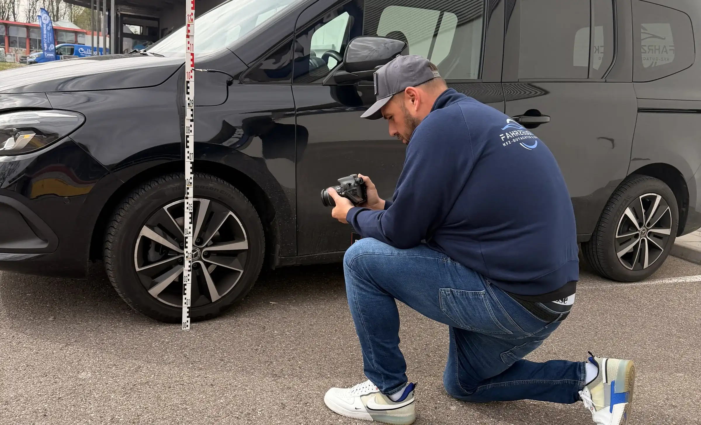 Kfz-Gutachter von Fahrzeugblick fotografiert einen Schaden an einem schwarzen Van in Augsburg