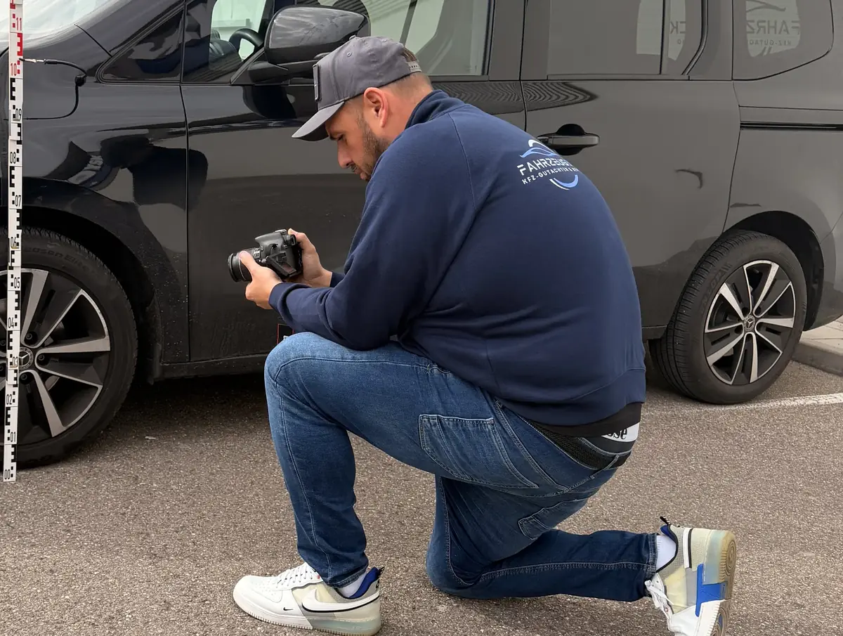 Gutachter dokumentiert mit der Kamera einen Unfallschaden an einem PKW